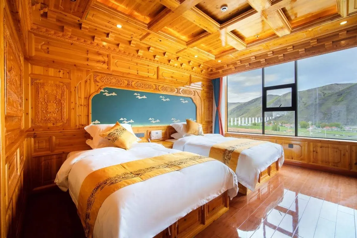 A cozy Tibetan-style hotel interior featuring wooden carvings, heated kang beds, and traditional tapestries