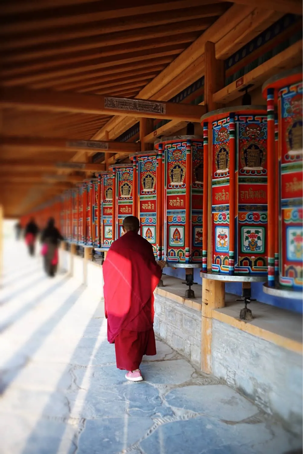 Tibetan pilgrims spinning a seemingly endless row of copper prayer wheels along the Labrang Kora