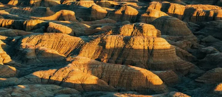 A breathtaking golden sunset over the vast desert Yardang formations with orange and purple twilight skies